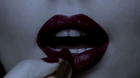 A sexy woman applies lipstick